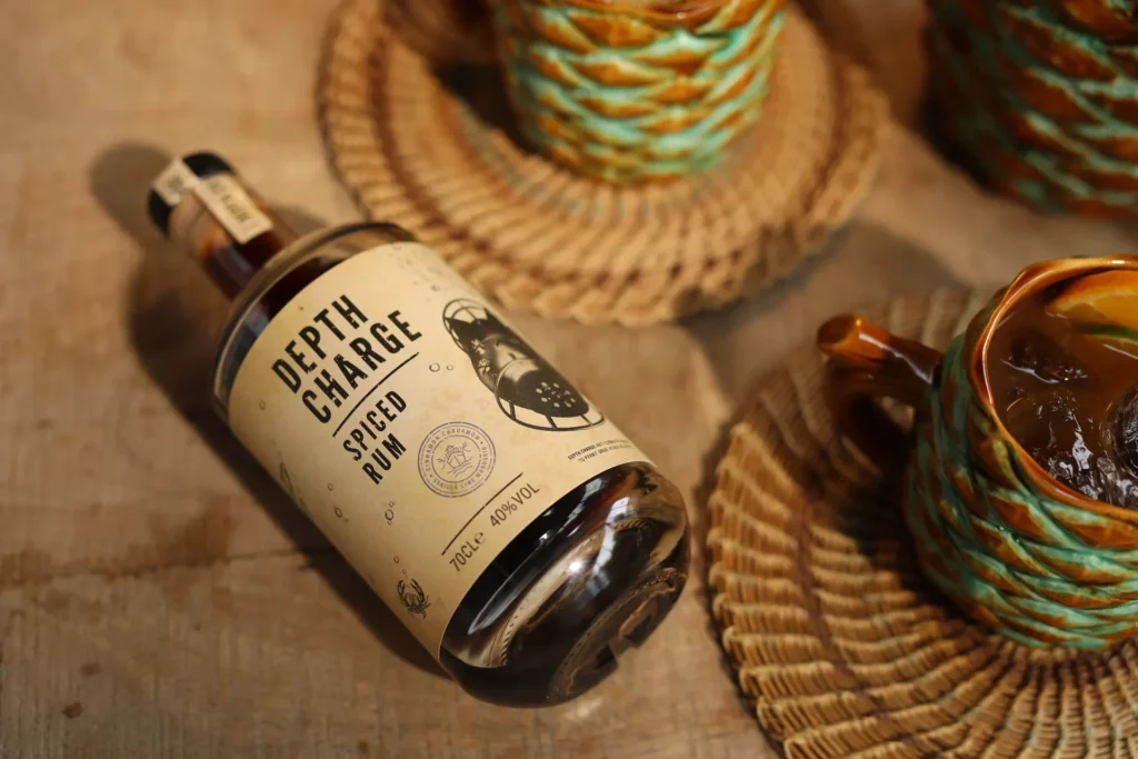 Depth Charge Spiced Rum bottle with vintage-style label and tiki cocktail props.