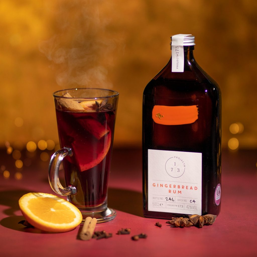 Rum label design for Project 173 Gingerbread Rum, amber bottle with clean typography, seasonal spiced cocktail styling and warm festive backdrop.